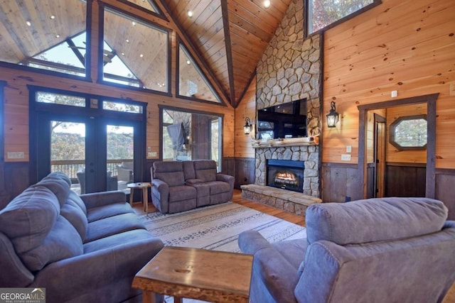 living room with hardwood / wood-style floors, wood walls, a fireplace, and high vaulted ceiling