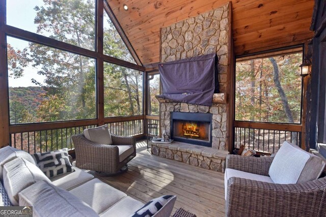 sunroom featuring a stone fireplace, wooden ceiling, and vaulted ceiling