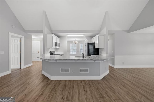 kitchen with lofted ceiling, white cabinets, kitchen peninsula, and stainless steel appliances