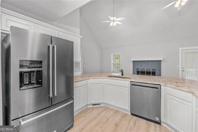 kitchen with sink, white cabinetry, light hardwood / wood-style floors, stainless steel appliances, and lofted ceiling