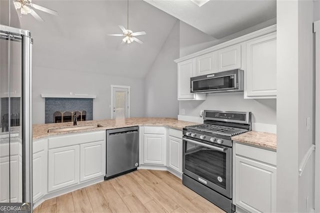 kitchen featuring vaulted ceiling, appliances with stainless steel finishes, white cabinets, and light hardwood / wood-style floors