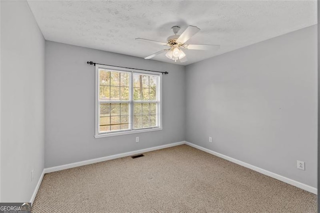 carpeted spare room with a textured ceiling and ceiling fan