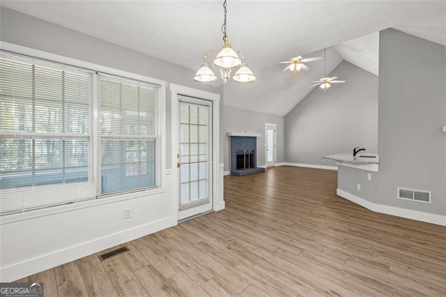 unfurnished living room with vaulted ceiling, wood-type flooring, and ceiling fan with notable chandelier