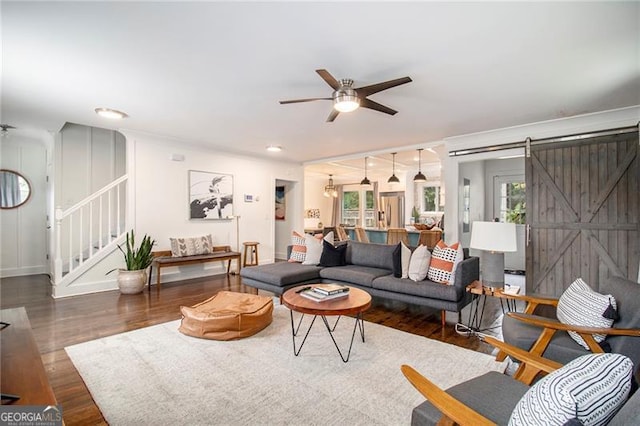 living room featuring ceiling fan, dark hardwood / wood-style flooring, and a barn door