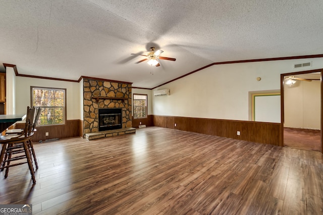 unfurnished living room featuring ceiling fan, wood-type flooring, a fireplace, and a textured ceiling