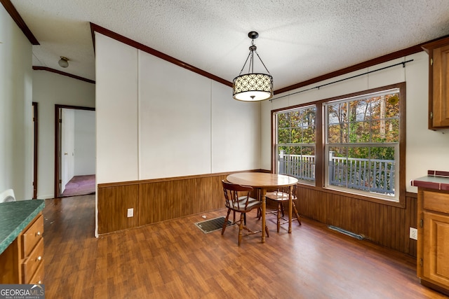 dining area featuring crown molding, dark wood-type flooring, and a textured ceiling