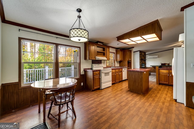 kitchen featuring sink, white appliances, hanging light fixtures, a textured ceiling, and a kitchen island