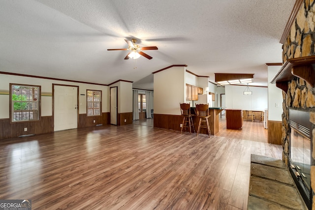 unfurnished living room featuring ceiling fan, hardwood / wood-style flooring, a textured ceiling, and wood walls