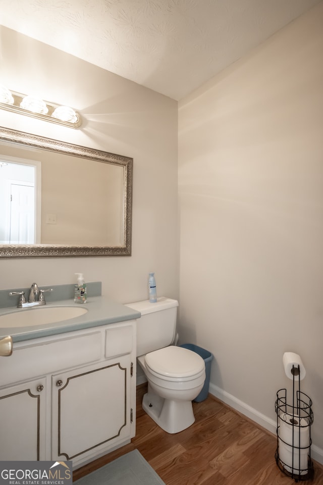 bathroom featuring toilet, a textured ceiling, hardwood / wood-style flooring, and vanity