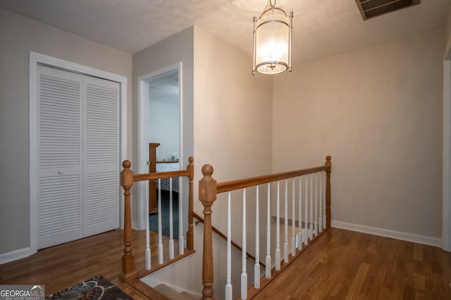 staircase with hardwood / wood-style floors and a notable chandelier