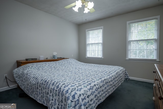 bedroom with multiple windows, dark carpet, and ceiling fan