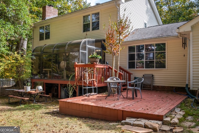 rear view of house featuring a wooden deck and a sunroom