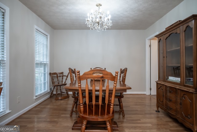 dining room featuring an inviting chandelier, a textured ceiling, and wood-type flooring