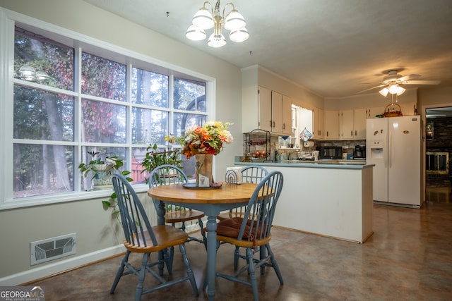 dining space with ceiling fan with notable chandelier