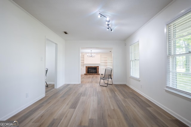 unfurnished living room featuring a fireplace, built in features, hardwood / wood-style flooring, and a healthy amount of sunlight