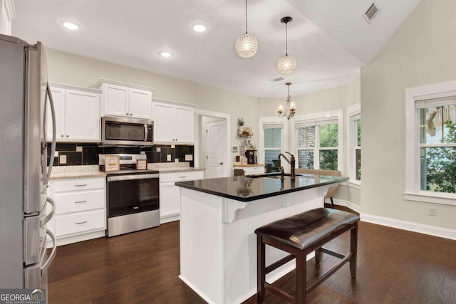 kitchen with white cabinets, a center island with sink, sink, decorative light fixtures, and stainless steel appliances