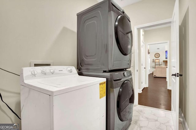 clothes washing area featuring light hardwood / wood-style flooring and stacked washer and dryer