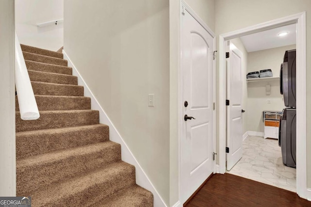 stairs featuring stacked washer / drying machine and hardwood / wood-style flooring