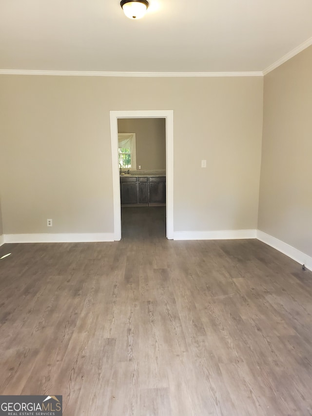 empty room with ornamental molding and hardwood / wood-style floors