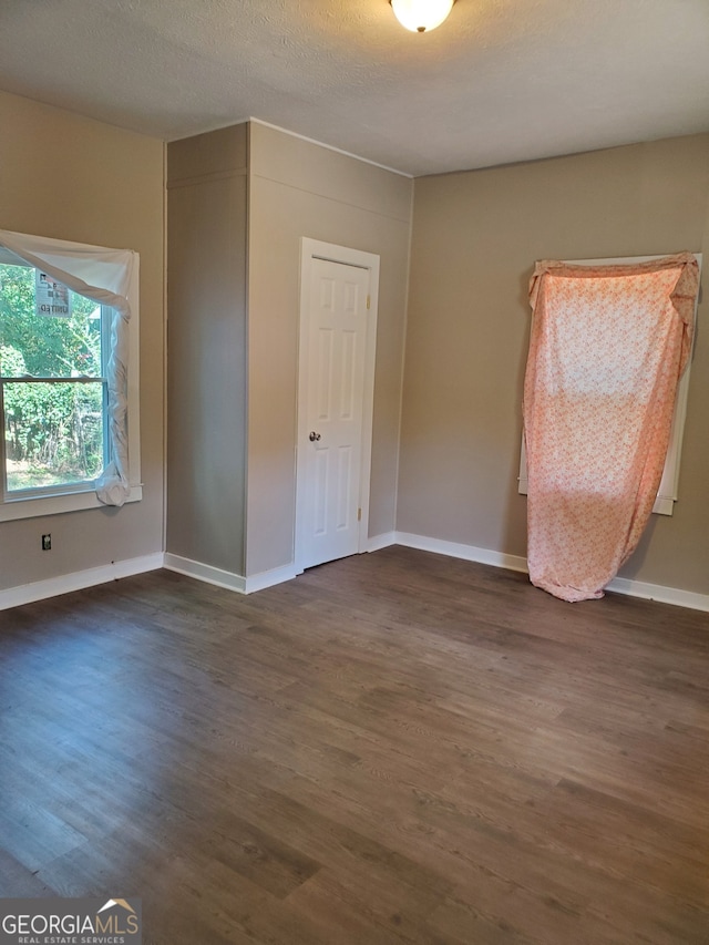 unfurnished room featuring dark wood-type flooring and a textured ceiling