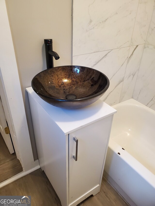 details featuring sink, a bathtub, and hardwood / wood-style flooring