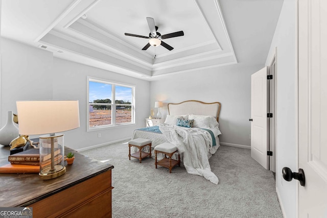 bedroom with a tray ceiling, light colored carpet, and ceiling fan