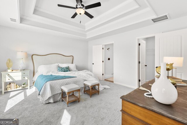 carpeted bedroom with ceiling fan, a walk in closet, and a tray ceiling