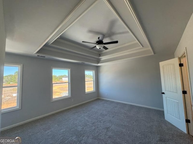 empty room with carpet flooring, ornamental molding, and a raised ceiling