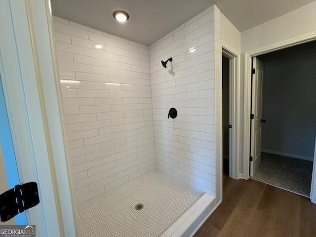 bathroom with wood-type flooring and a tile shower