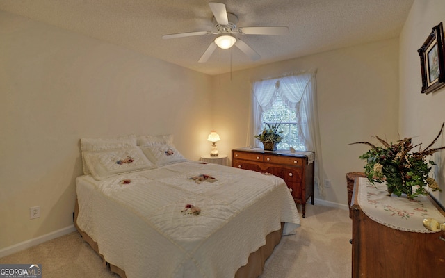 bedroom featuring light carpet, a textured ceiling, and ceiling fan