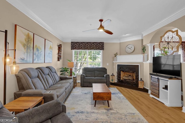 living room with ceiling fan, light wood-type flooring, and ornamental molding