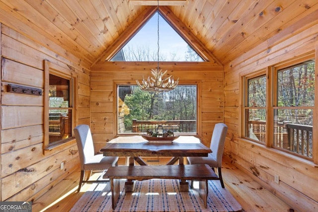 dining room with light hardwood / wood-style floors, a notable chandelier, and wood walls