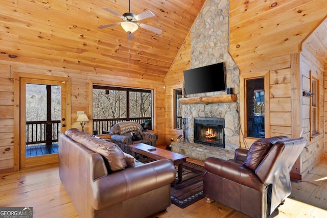 living room with wood walls, light wood-type flooring, wood ceiling, a stone fireplace, and high vaulted ceiling