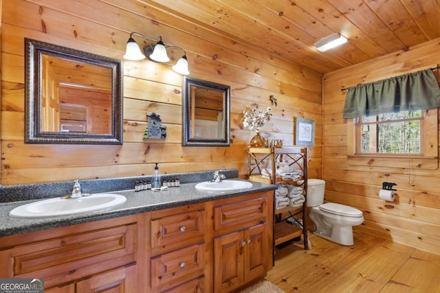 bathroom featuring wood walls, toilet, wooden ceiling, vanity, and hardwood / wood-style flooring