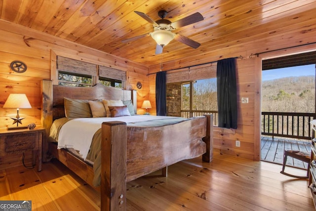 bedroom featuring light hardwood / wood-style floors, wooden walls, and ceiling fan