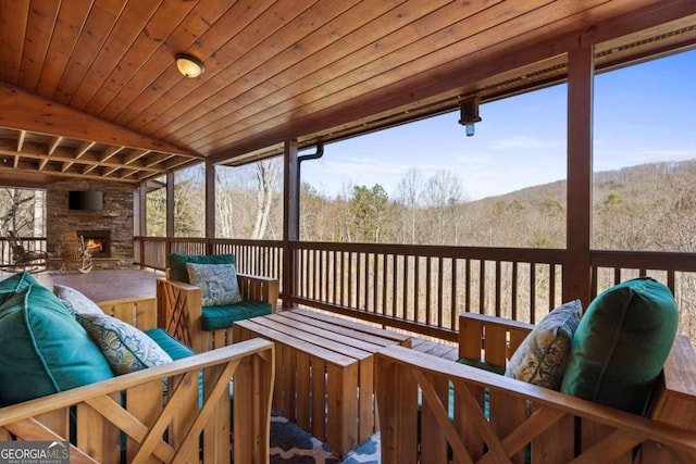 wooden terrace featuring an outdoor stone fireplace