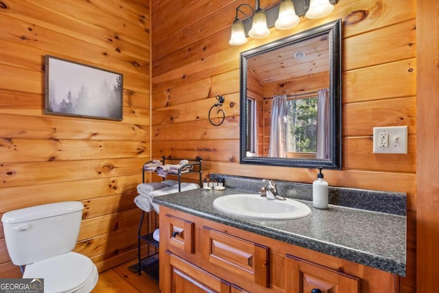 bathroom with vanity, wood walls, toilet, and wood-type flooring