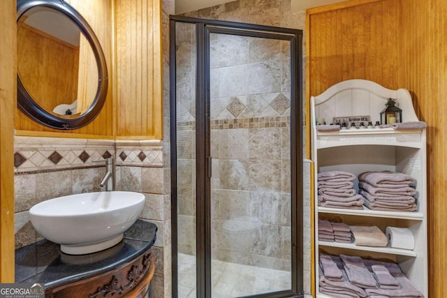 bathroom with a shower with door, vanity, and tile walls