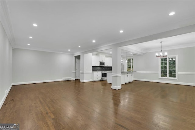 unfurnished living room with dark wood-type flooring, a chandelier, and ornamental molding