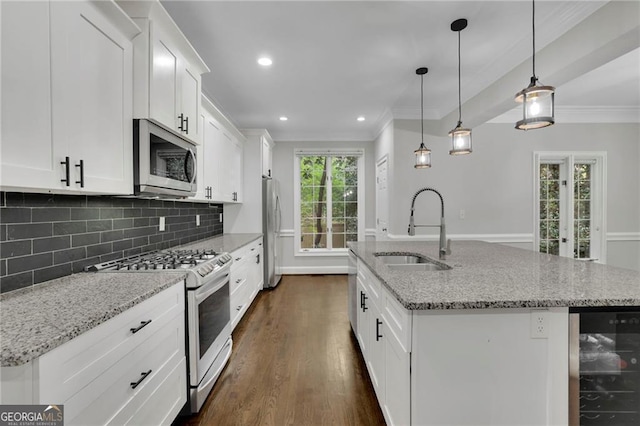 kitchen with decorative light fixtures, sink, an island with sink, stainless steel appliances, and beverage cooler