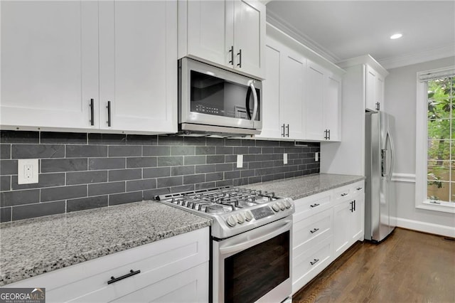 kitchen featuring white cabinetry, appliances with stainless steel finishes, tasteful backsplash, light stone countertops, and ornamental molding