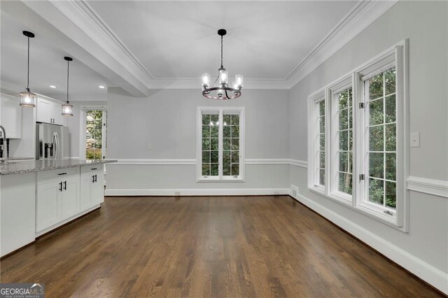 unfurnished dining area featuring dark wood-type flooring, a notable chandelier, sink, and ornamental molding