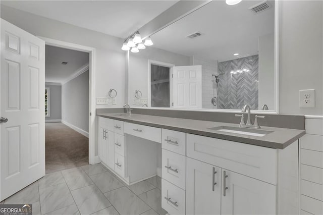 bathroom with a tile shower, vanity, and ornamental molding