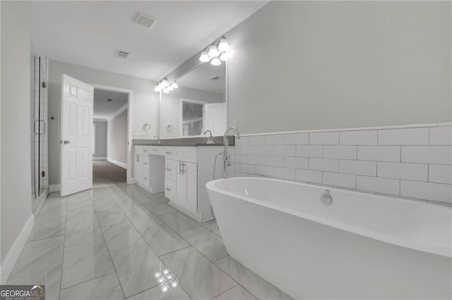 bathroom featuring vanity, ornamental molding, and a tub