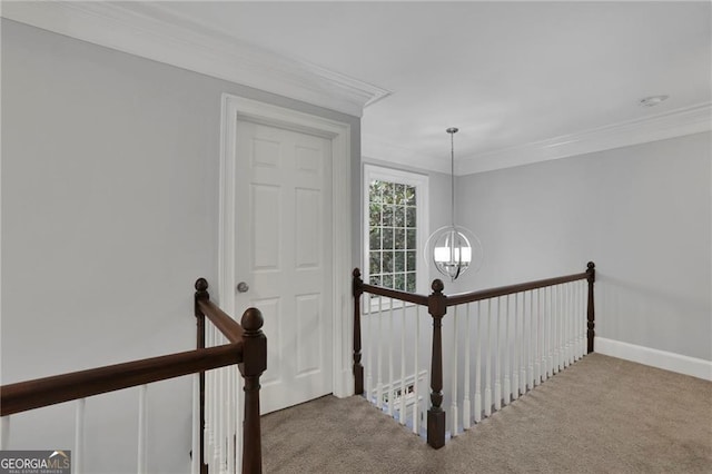 corridor with carpet floors, crown molding, and an inviting chandelier