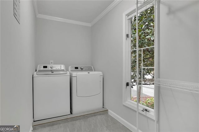 clothes washing area with a wealth of natural light, crown molding, and washer and clothes dryer