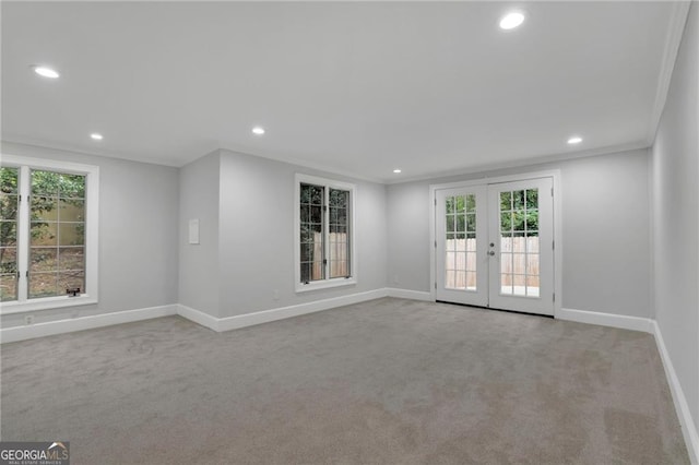 empty room with light colored carpet, french doors, crown molding, and a healthy amount of sunlight