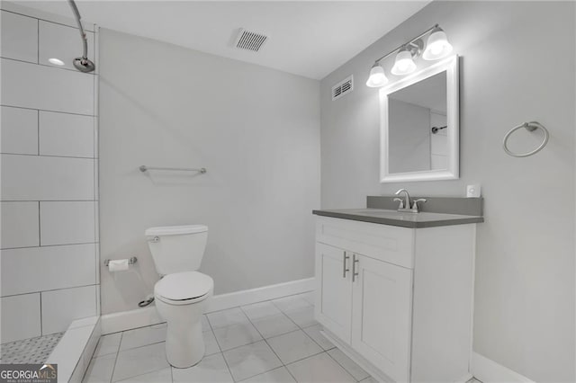 bathroom with tile patterned floors, toilet, vanity, and a tile shower