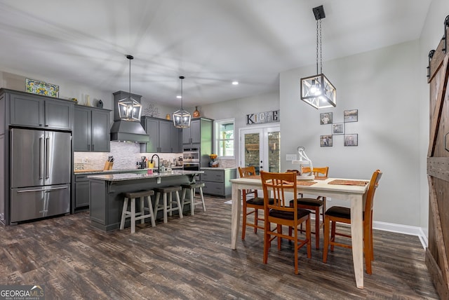 dining room featuring sink, dark hardwood / wood-style floors, french doors, and a barn door