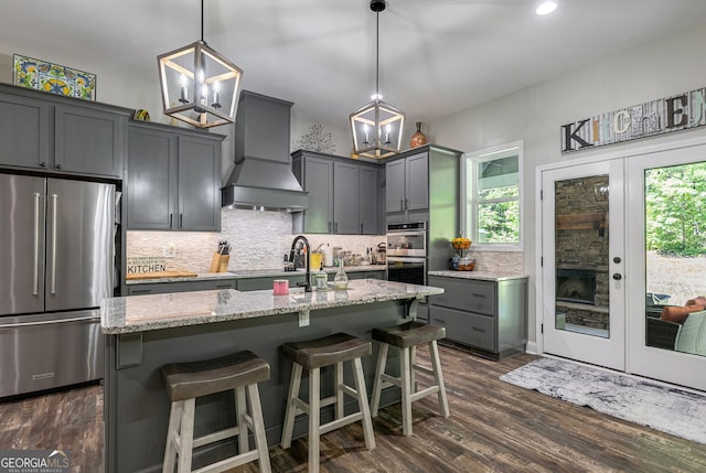 kitchen featuring hanging light fixtures, premium range hood, appliances with stainless steel finishes, and plenty of natural light